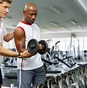 A man getting instructed on how to lift a dumbbell